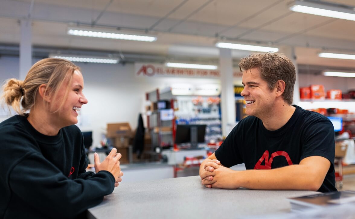 To AO medarbejder snakker smilende til hinanden i AO butik